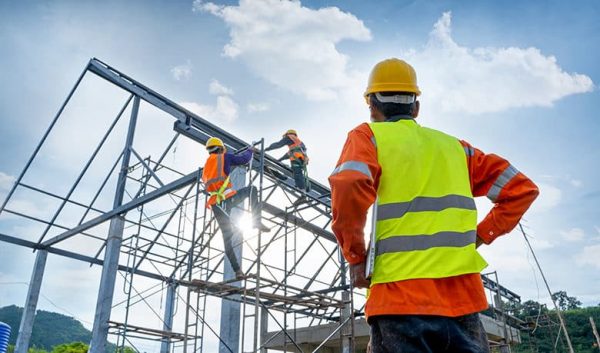 Engineer technician watching team of workers on high steel platform.